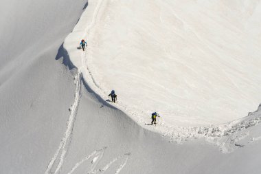 Fransız Alplerinde, Chamonix 'deki Mont Blanc sıradağlarında, karla kaplı bir sırt boyunca yürüyen üç dağcı var..