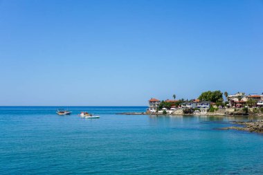 Üzerinde birkaç teknenin yüzdüğü sakin mavi bir deniz, Antik Liman. Su berrak ve gökyüzü parlak mavi.