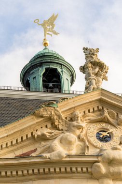 Munster Almanya 'sında yeşil çatılı ve tepesinde heykeli olan büyük bir bina. Binanın bir sürü penceresi ve bir saat kulesi var. Gökyüzü mavi ve arka planda bazı ağaçlar var..