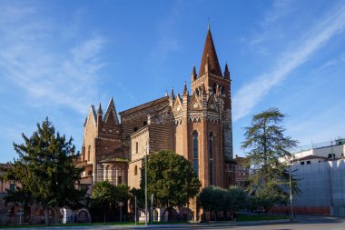 İtalya 'nın Verona şehrinde beyaz elementli kırmızı tuğladan yapılmış antik bir kilise binası. Gökyüzü mavi, güneşli ve açık bulutlu..
