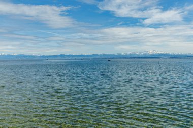 Alman tarafındaki Bodensee Gölü 'nde yüzen çok sayıda yelkenli vardı. Arka planda karla kaplı Alp dağlarından oluşan bir manzara var. Fotoğraf güneşli bir günde çekildi. Su temiz..