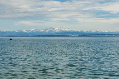 Alman tarafındaki Bodensee Gölü 'nde yüzen çok sayıda yelkenli vardı. Arka planda karla kaplı Alp dağlarından oluşan bir manzara var. Fotoğraf güneşli bir günde çekildi..