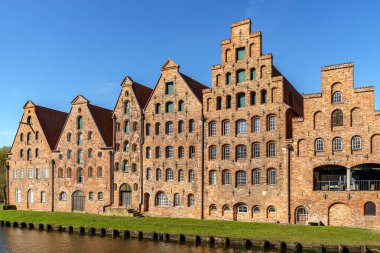 Almanya 'nın Lubeck şehrinde bir dizi eski kırmızı tuğla bina. Gökyüzü mavi ve parlak. Hava güneşli..