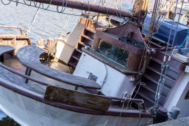 Suda tahta bir masa ve penceresi olan bir tekne oturuyor. Tekne eski görünüyor ve terk edilmiş..