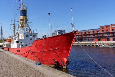 Lubeck Almanya 'sında büyük bir kırmızı gemi rıhtıma yanaştı. Gemi bir zincir ve şamandırayla çevrili. Sahne sakin ve huzurlu, su ve gökyüzü sakin bir zemin sağlıyor..