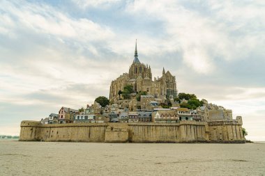 Normandiya, Fransa 'daki Mont Saint Michel Manastırı, öğleden sonra erken saatlerde fotoğraflandı. Gökyüzü mavi ve bulutlu. Kalenin yakınında kimse yok. Fotoğraf gelgit sırasında çekildi..