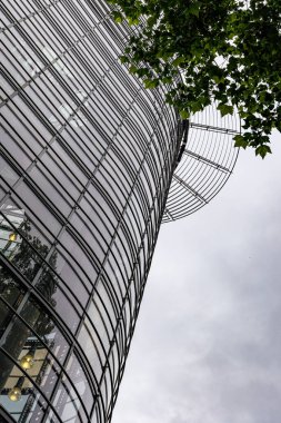 Hanover Almanya 'sında üzerinde ağaç büyüyen yüksek bir bina. Gökyüzü bulutlu ve bina camla kaplı..