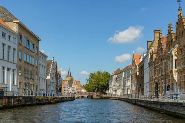 Belçika 'nın Bruges şehrindeki bir kanaldan bir sokak manzarası. Duvarın solunda ve sağında farklı renkte evlerden oluşan bir sıra var..