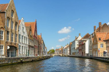 Belçika 'nın Bruges şehrindeki bir kanaldan bir sokak manzarası. Duvarın solunda ve sağında farklı renkte evlerden oluşan bir sıra var..