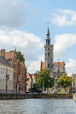 Brüj, Belçika 'da setin manzarası ve Gotik bir kilise. Soldaki setin üzerinde bir sıra ev görülebilir. Bina beyaz ve kırmızı, kilise uzun ve yüksek bir kulesi var..