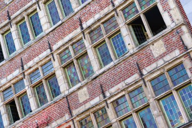 Gent, Belçika 'da birçok kare pencereli eski bir kırmızı tuğla binanın ön cephesi..