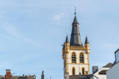 Almanya 'nın Trier şehrinde sivri siyah çatılı kare bir kule. Kulenin tepesinde bir haç var, horoz değil..