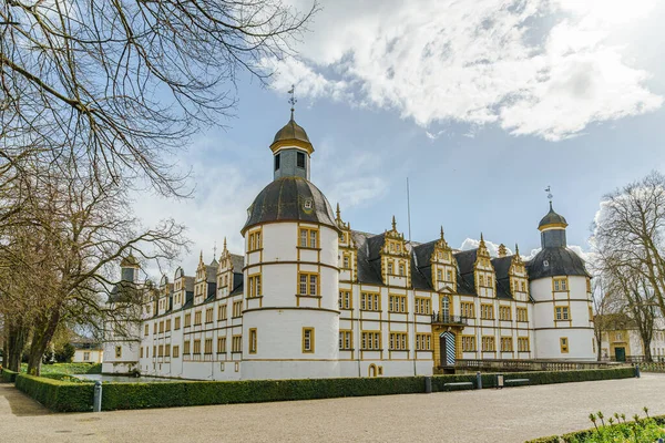 Paderborn Almanya 'sında Neuhaus Kalesi' nin önünde avlusu olan büyük beyaz bir bina. Avlu bir çakıl yolu ile çevrili ve bir sürü çiçek var..