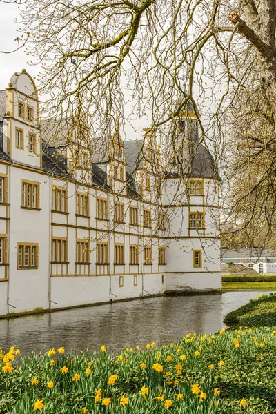 Paderborn Almanya 'sında Neuhaus Kalesi' nin önünde bir kule ve gölet olan bir bina. Gölet sakin ve bina beyaz..