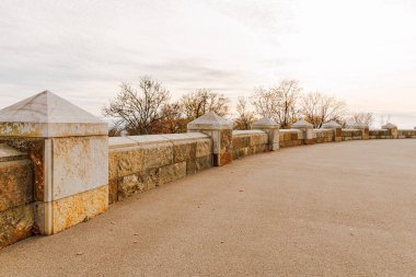 Almanya 'nın Porta Westfalica bölgesindeki Wilhelm Anıtı' nda bir sıra taş sütun. Sütunlar beyaz ve gri. Gökyüzü bulutlu ve güneş batıyor..