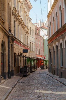 Letonya 'nın Riga şehrinde birkaç dükkan ve restoranın olduğu dar bir sokak. Sokak tuğla binalarla kaplı ve kaldırım taşı yüzeyi var..