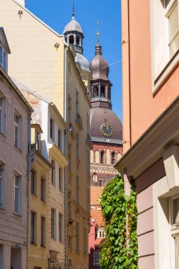 Eski evleri ve Riga, Letonya 'nın ortasından görünen Kubbe Kilisesi' nden bir kulesi olan dar bir sokak. Mavi gökyüzü görünür.