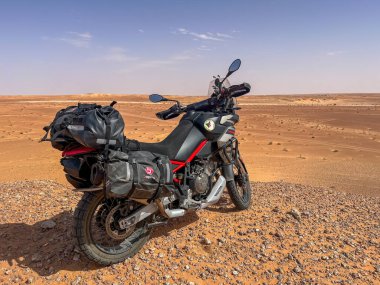 Cezayir Sahra Çölü 'nün taşlı çölüne park etmiş dolu bir motosiklet..