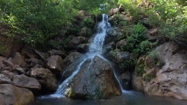 Cascading natural waterfall, clear water, rocky bottom, green trees, High quality photo