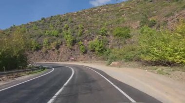 Güneşli yol ağaçları. Dağ yolu ağaçları. Yüksek kalite FullHD görüntüleri.