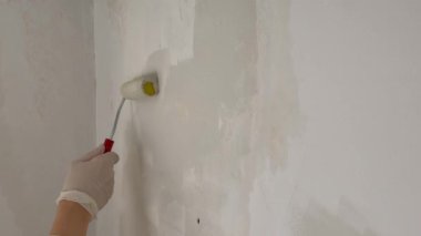 Duvarı boyayan kişi. Bir ressam silindirle beyaz bir duvar boyuyor. Yüksek kalite 4k görüntü