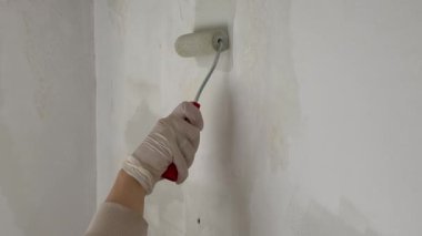 Duvarı boyayan kişi. Bir ressam silindirle beyaz bir duvar boyuyor. Yüksek kalite 4k görüntü
