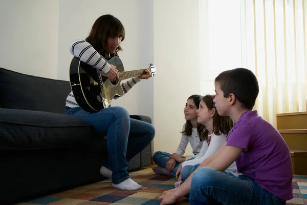 Mulher Alegre Tocando Guitarra Para Crianças Sala Estar Casa — Fotografia de Stock