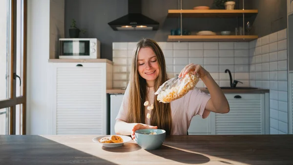 Alegre Hembra Vertiendo Cereal Crujiente Tazón Mesa Con Sabrosas Galletas — Foto de Stock