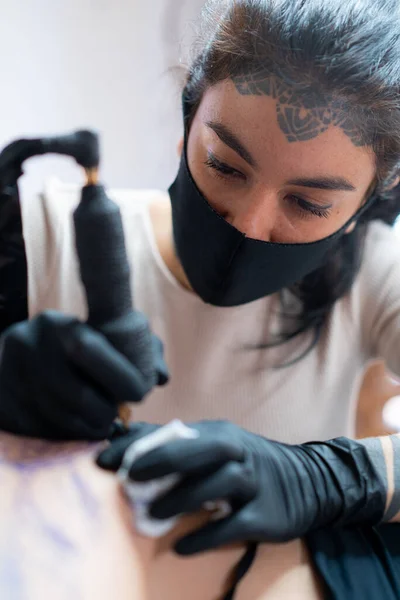 女性のタトゥーで布面マスクでマシン描画入れ墨体上の認識できないクライアントでサロン — ストック写真