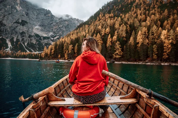 在意大利白云岩高地壮丽景色的背景下 隐约可见的金发女子坐在木船上 划着桨 漂浮在平静的湖水中 望向远方 — 图库照片