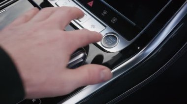 Otomotiv pazarlama ve yaşam tarzı kavramları için konaklama teknolojisi kolaylığını ve çağdaş araç tasarımını sembolize eden, modern bir arabanın içinde motoru çalıştırma durdurma düğmesine basan bir sürücünün videosunu kapat.