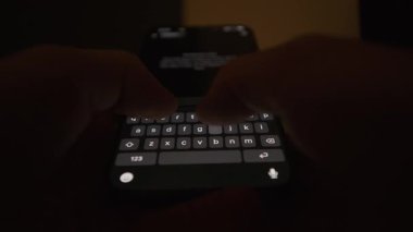 Karanlık bir ortamda akıllı bir telefona, yapay zeka etkileşimini, modern teknoloji ve dijital iletişim kavramlarını gösteren ekran klavyesine odaklanarak büyük bir dil modeline komut yazma videosunu kapat.