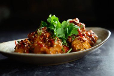 Üstünde yeşil garnitür olan bir tabak yemek. Tabak yemek dolu ve lezzetli görünüyor.