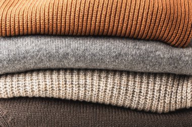 Sıcak renklerde örülmüş yün kazak yığını. Sıcaklık ve rahatlık. Kış giysileri.