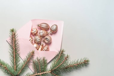 Yeşil arka planda Noel ağacı süslemeleri olan pembe bir zarf. Mutlu tatiller. Noel kartı..