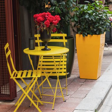 Sarı masa ve bir kafede sandalyeler. Sarı saksı. Seçici odak.