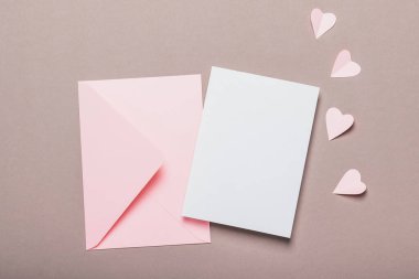 Pembe zarf ve kahverengi arka planda boş form. Kağıt pembe kalpler. Sevgililer Günü konsepti.