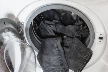 Çamaşır makinesinde siyah kot pantolon. Çamaşır günü tam bir yükle başlar.