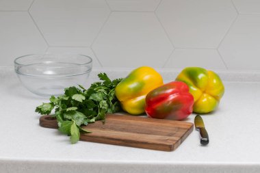 Beyaz mutfak tezgahında çok renkli biber ve taze kereviz. Canlı ve sağlıklı bir aşçılık sahnesi, yaratıcı aşçılığa hazır..