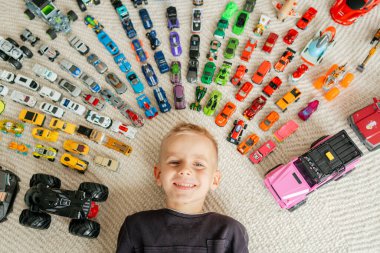 Halıdaki minyatür araçlar, parlak oyuncaklar ve neşeli ifadelerle çerçevelenmiş mutlu çocuk neşeli bir kompozisyon oluşturur