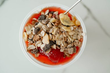 Healthy breakfast bowl with yogurt, strawberry jam and crunchy muesli on white background. Close-up of nutritious food