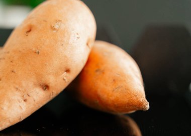 Tatlı patatesler parlak karanlık arka planda doğal sağlıklı kök sebze konsepti