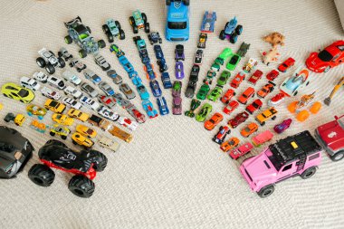 Renkli oyuncak arabaların yukarıdan aşağı görünümü halı koleksiyoncusu ekranında sıralı yarım daire şeklinde düzenlenmiş ve oyuncu desenler