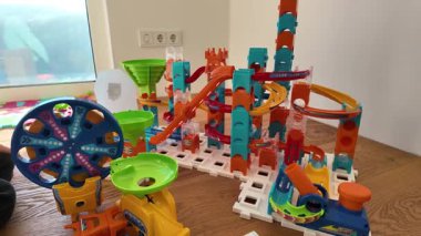 Ahşap bir yüzeye, halka, huni ve rampalarla dolu renkli bir mermer konur. Parlak plastik elementler yaratıcılık ve BTMM öğrenimi kavramları için dinamik ve eğlenceli bir sahne yaratıyor.