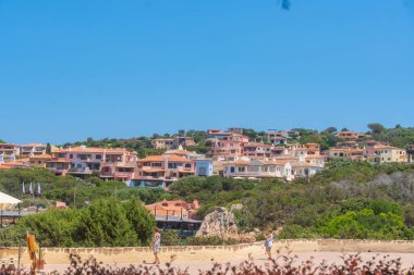 07.04.25, Porto Cervo, İtalya, Sahil tatil köyü açık mavi gökyüzü altındaki tepeler üzerinde binalar. Akdeniz seyahati, yaz tatili ve kıyı yaşam tarzı