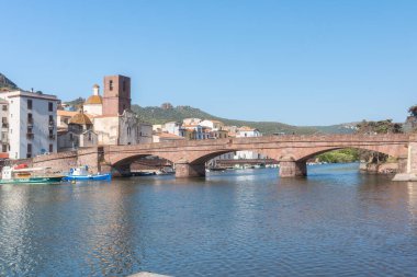 Avrupa 'da sakin bir nehri geçen tarihi bir taş köprünün manzarası. Sıcak güneş ışığı mimariye vurgu yaparak, seyahate yönelik barışçıl bir atmosfer yaratıyor, Bosa, Italien