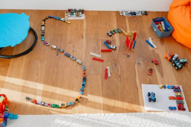 Ahşap zemine yayılmış renkli oyuncaklardan oluşan parlak bir çeşitlilik. Bloklar, izler ve elementler çocukluk gelişimi, oyun zamanı, hayal gücü temaları için mükemmel bir yaratıcı sahne oluşturur.