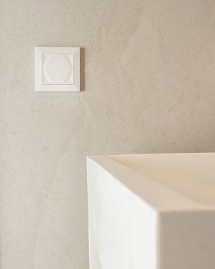 Beyaz lavabonun yanında modern bir lamba düğmesine yakın çekim. Yumuşak ışıklandırma ve pürüzsüz yüzeyler, ev tasarımı, teknoloji ve iç temalar için uygun temiz ve basit bir görünümü vurgular