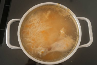 Çorbada erişte ve sebzelerle birlikte ocakta kaynayan tavuk çorbası. Sıcak, ev yapımı yemekler konforu, ev yemeklerini ve basit bir geleneksel yemeğin hazırlanmasını sağlar.