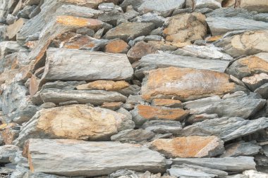 Yığılmış düz taşların yakın çekimi doğal bir duvar dokusu oluşturuyor. Tasarım ve mimari kavramlar için kırsal arkaplan